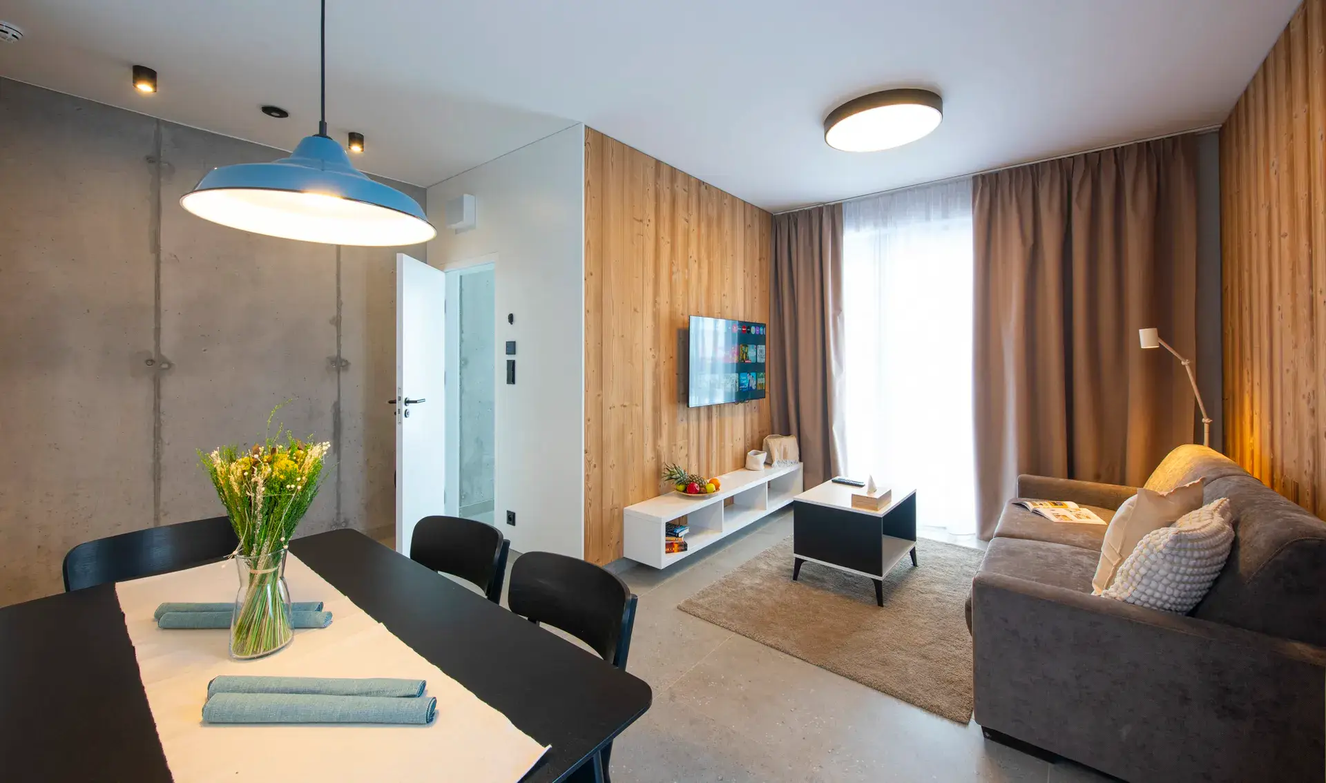 Obývacia časť s jedálenským stolom vo vzorovom menšom apartmáne LUXURY